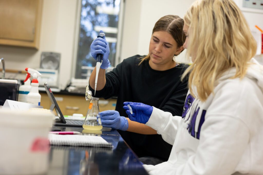 Two biology students with a beaker doing an experiment.