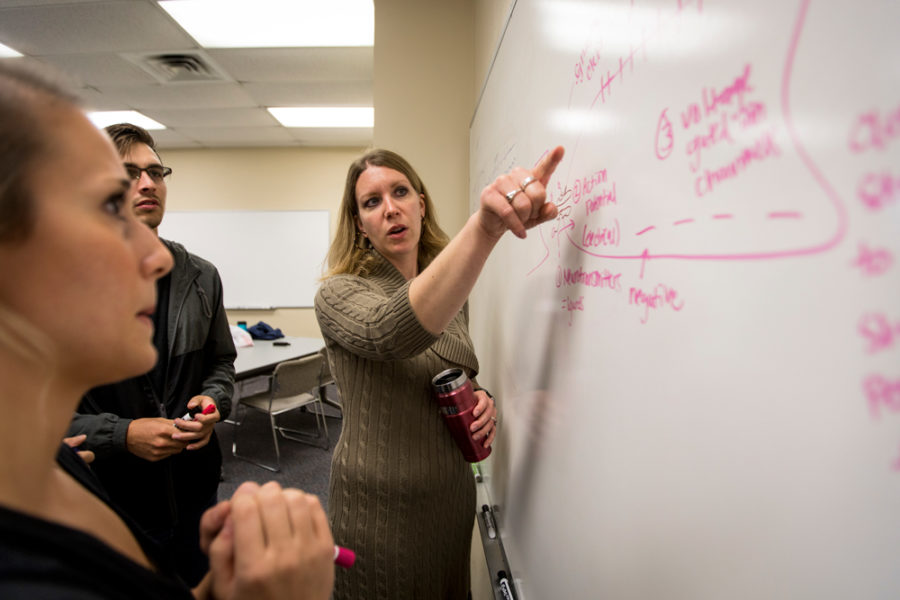 Student pointing to work written on whiteboard while teaching students