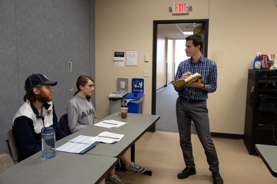 CSP Professor lecturering in a classroom settting. Two students sitting at a desk listening