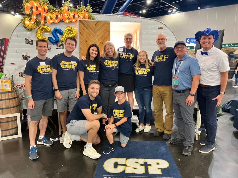 Group of CSP employees gathered in front of a white camper indoors