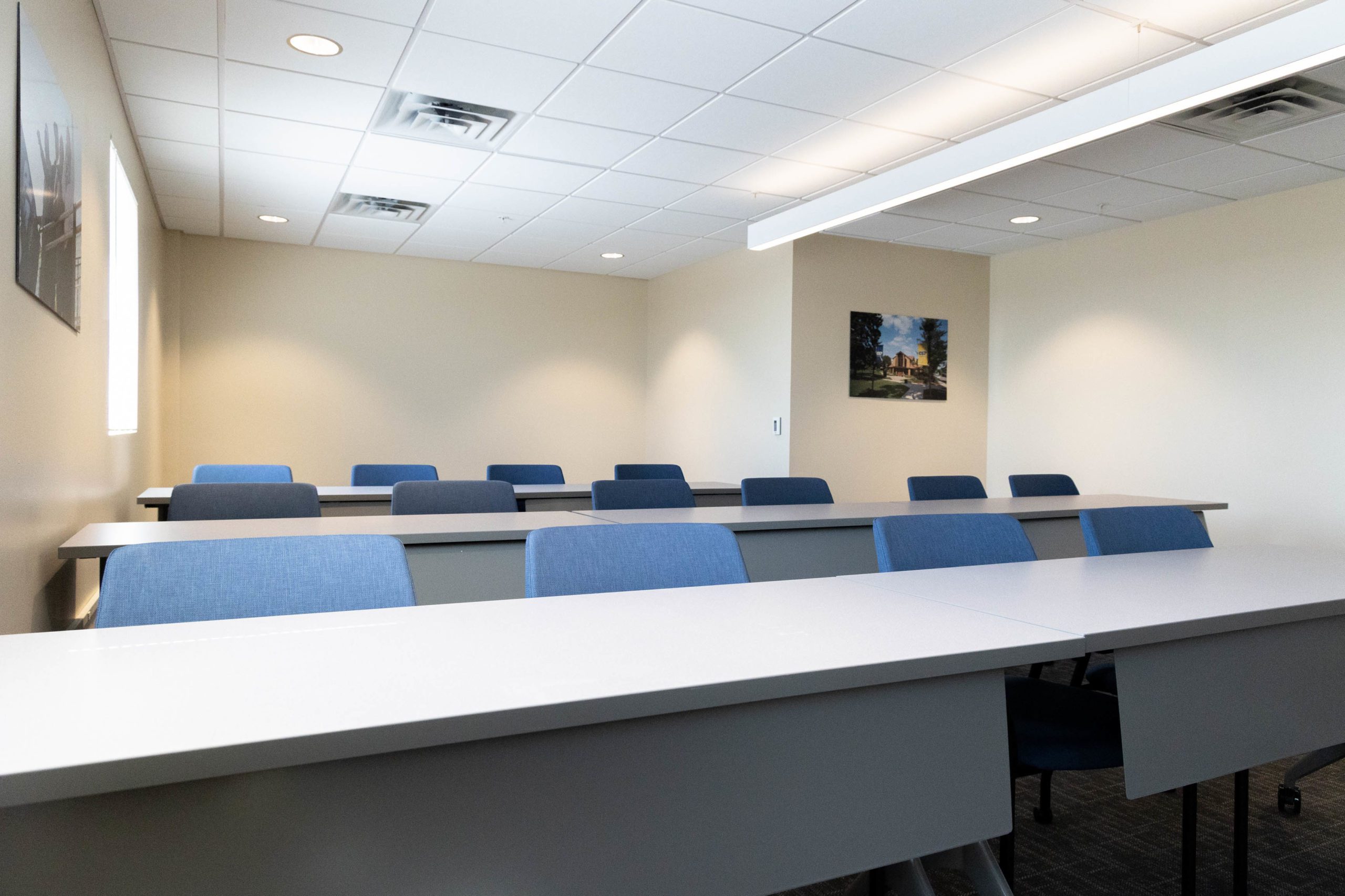 Classroom with gray tables in rows and blue chairs set at each table