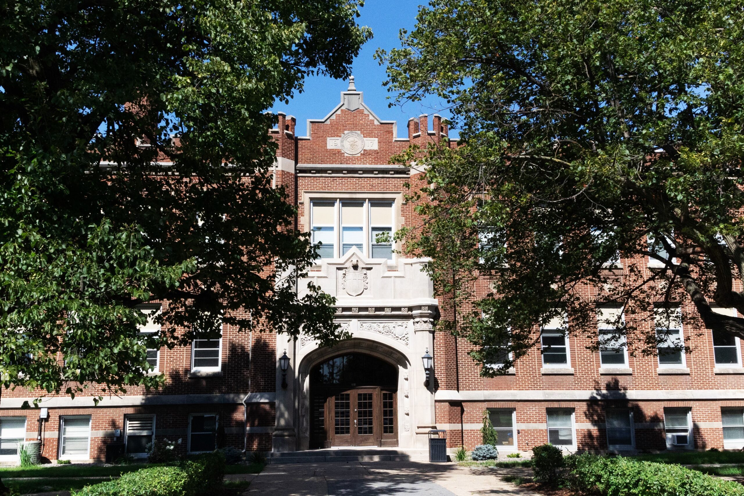 Meyer Hall with trees on both sides, blue sky, can see entrance doors.