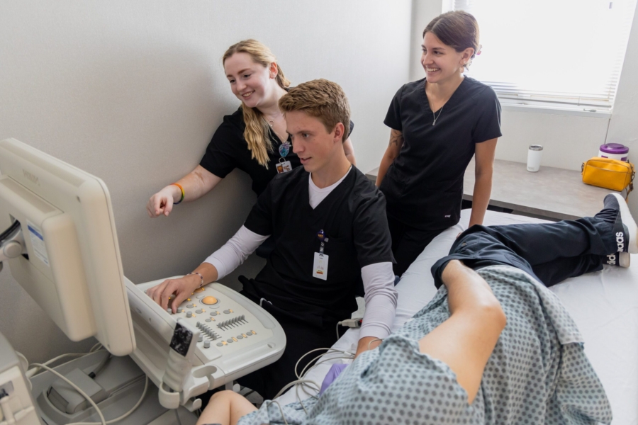 Three students working with diagnostic medical sonography equipment.