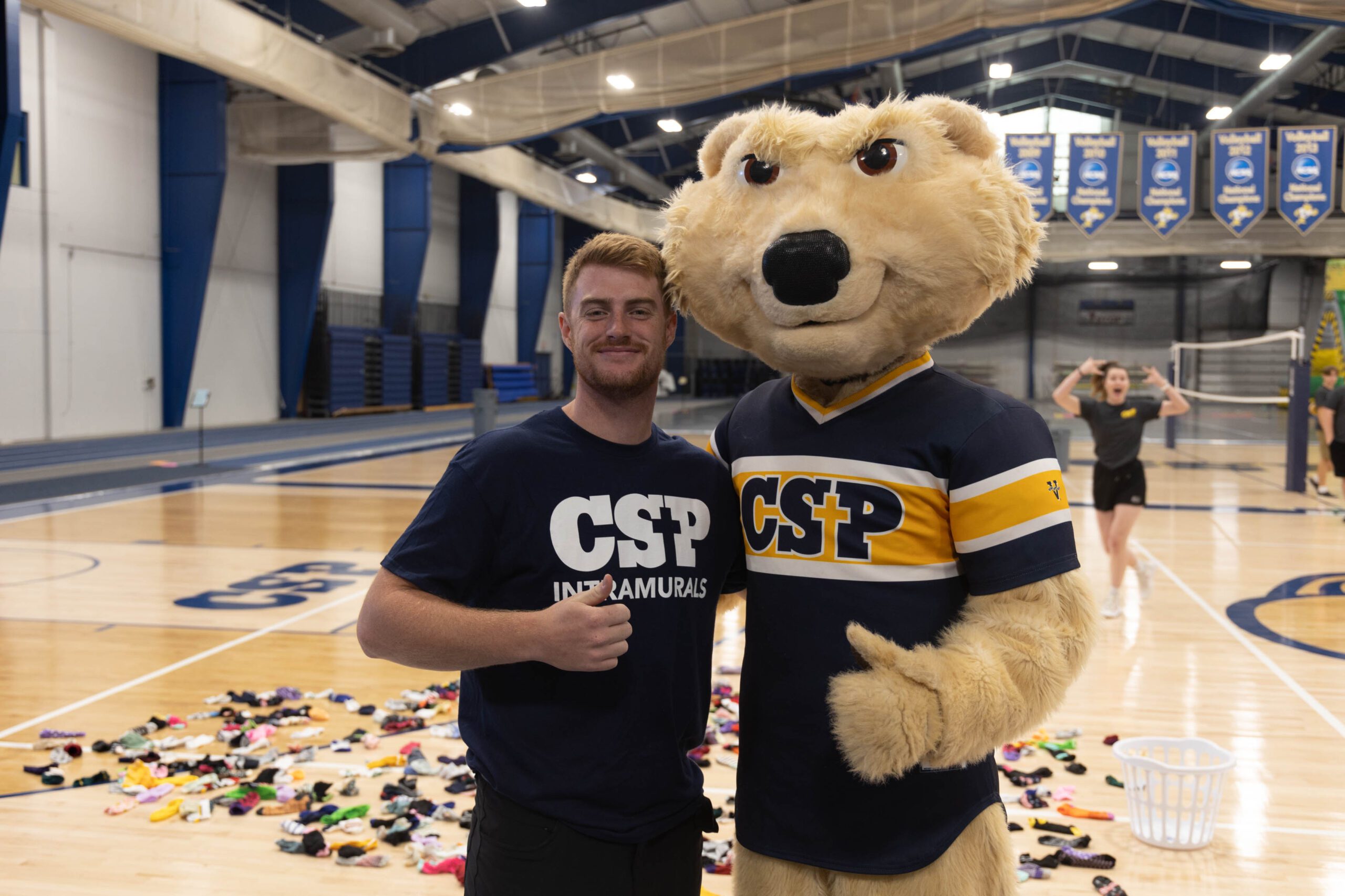 Student standing with a CSP Comet Bear mascot.