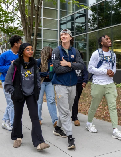 Group of students walking on a sidewalk on a college campus.