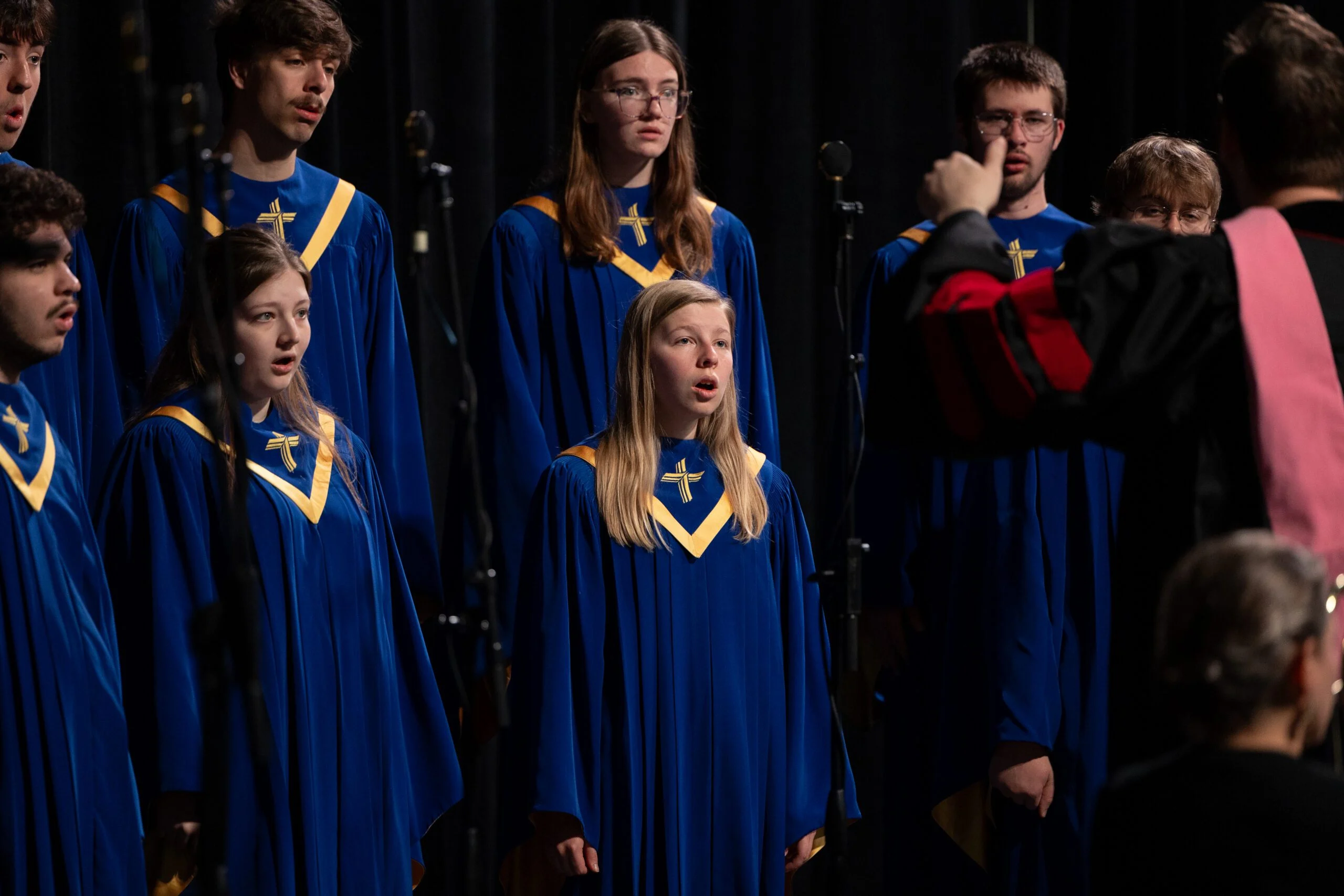 Group of students singing in a choir at CSP wearing blue robes.