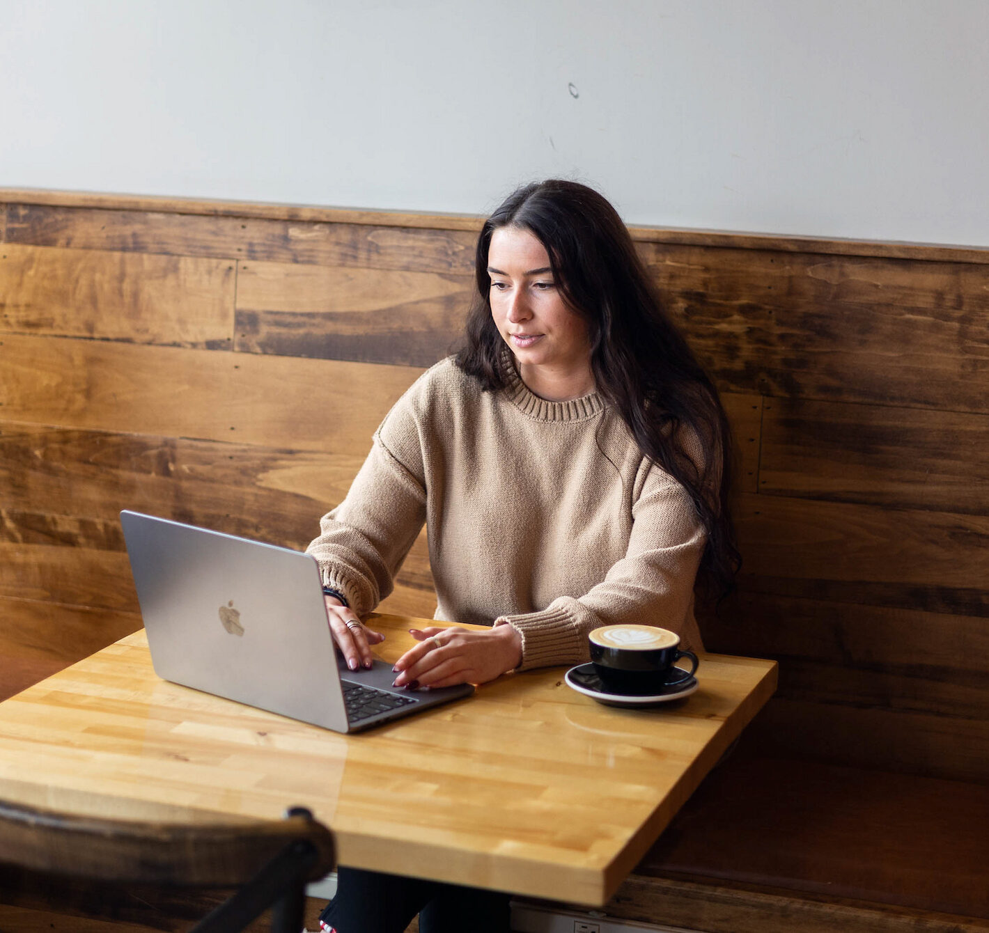 Student sitting at a coffee shop at a table using a laptop.