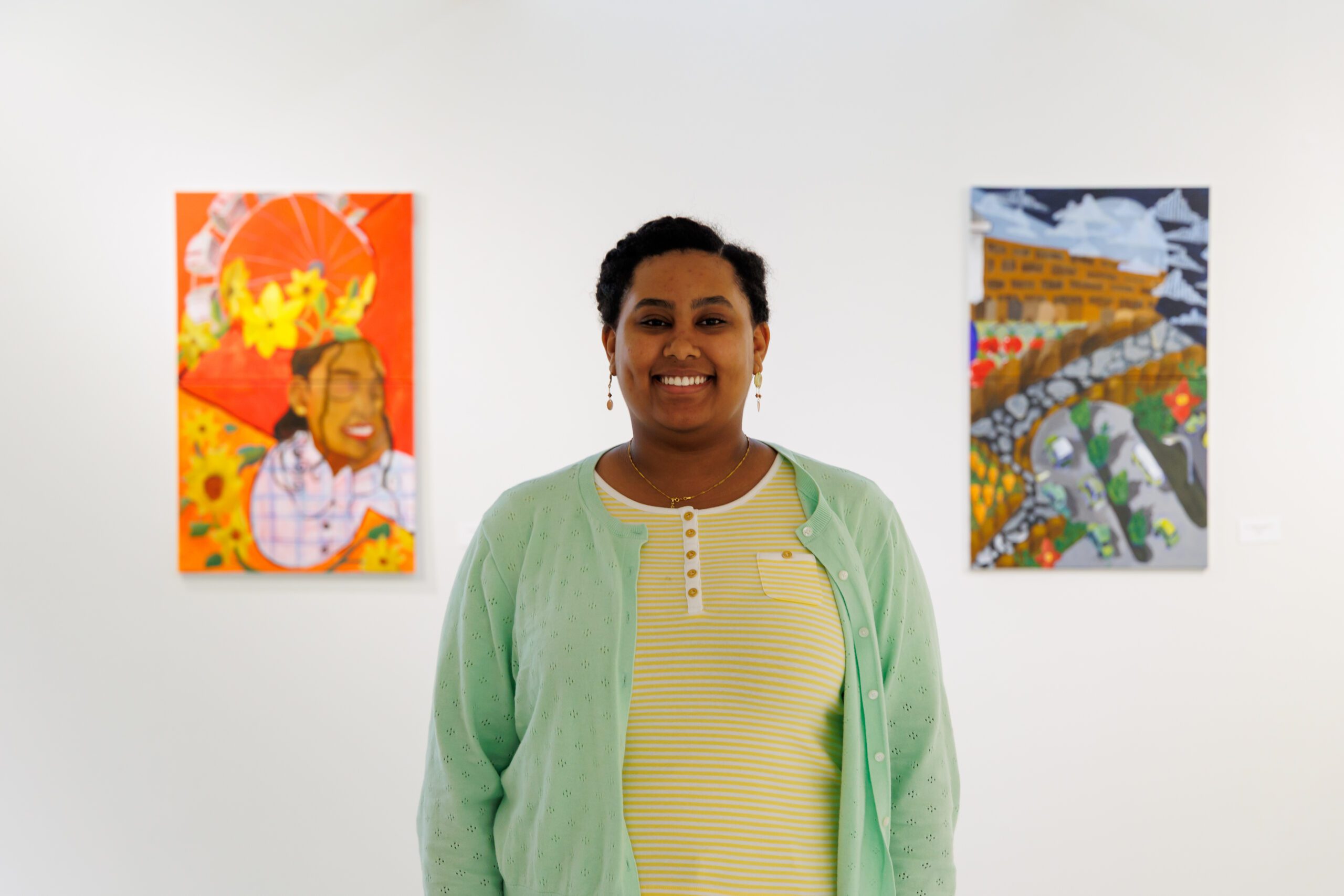 Headshot of CSP student Mikal Barnabas standing in front of two art pieces.
