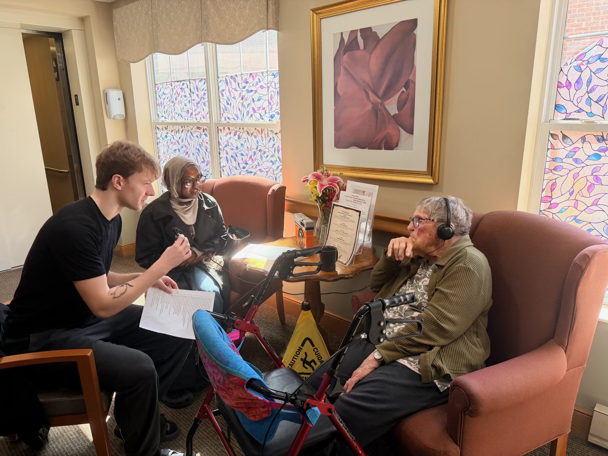 Two CSP students sit with older resident and converse.
