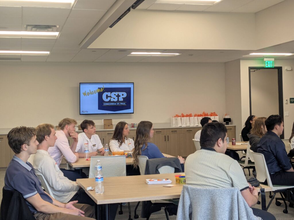 CSP students sitting at tables, listening to a speaker.