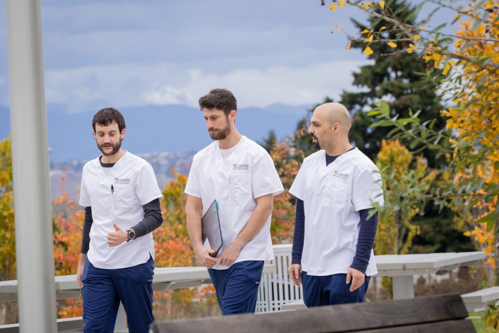 Group of three CSP nursing students wearing scrubs walking outside at the CSP Portland campus.