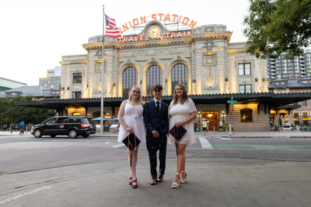 Group of three CSP nursing students with graduation caps standing in front of Denver's Union Station.